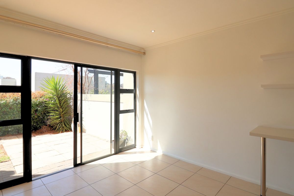 Bright and spacious living area featuring tiled floors, built-in shelving, and large sliding glass doors providing direct access to the outdoor patio area.