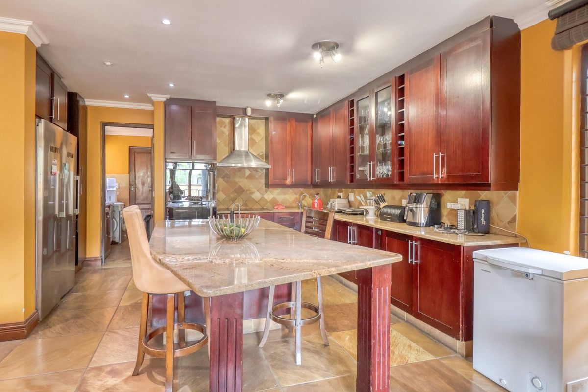 Spacious kitchen featuring dark wood cabinetry, granite countertops, a central island, and stone floor tiles, offering a functional layout with ample storage.
