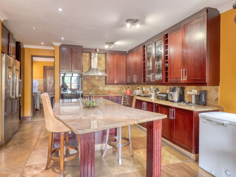 Spacious kitchen featuring dark wood cabinetry, granite countertops, a central island, and stone floor tiles, offering a functional layout with ample storage.