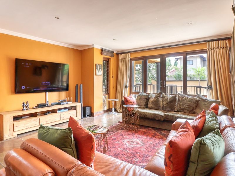 A spacious living room featuring tiled flooring, recessed lighting, and large sliding glass doors that provide access to the outdoor area.