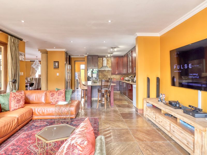 Spacious open-plan living area featuring a modern kitchen with island, tiled flooring, and seamless flow to the dining space and outdoor patio.