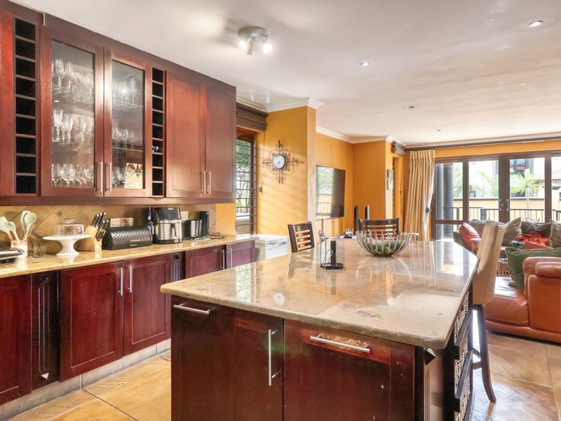 Open-plan kitchen and living area featuring dark wood cabinetry, granite countertops, a central island, and direct access to an outdoor patio.