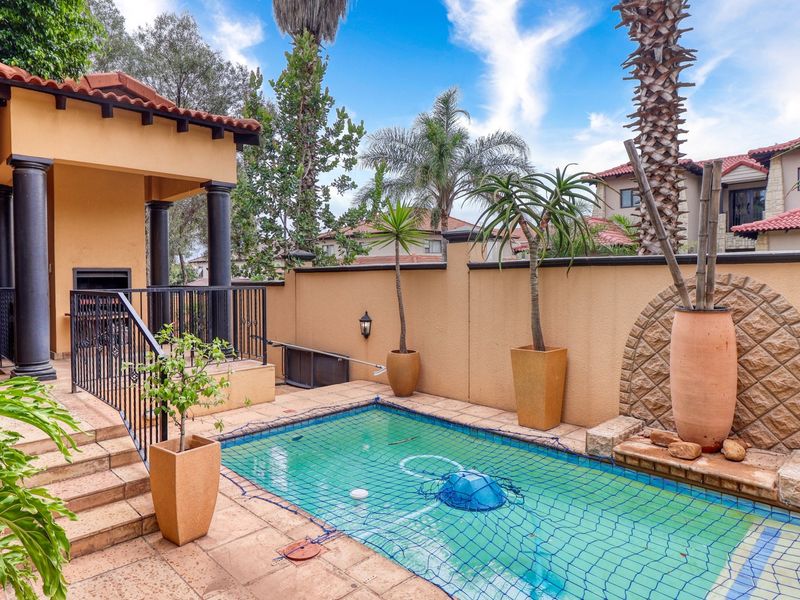 Outdoor pool area featuring a built-in braai, tiled patio space, and a decorative stone feature wall, perfect for entertaining.