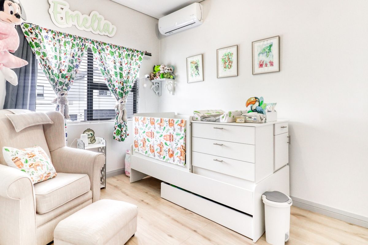 A well-maintained bedroom featuring light-toned laminate flooring, neutral wall finishes, and a wall-mounted air conditioning unit.