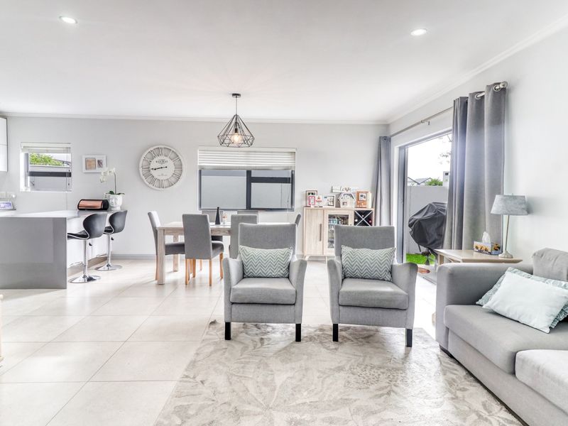 Spacious open-plan living area featuring a modern kitchen with island, tiled floors, and seamless flow to the outdoor patio through sliding glass doors.