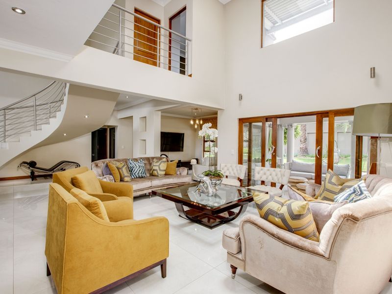 Spacious double-volume living room featuring a striking curved staircase, polished tile flooring, and large sliding doors providing seamless access to the outdoor patio area.