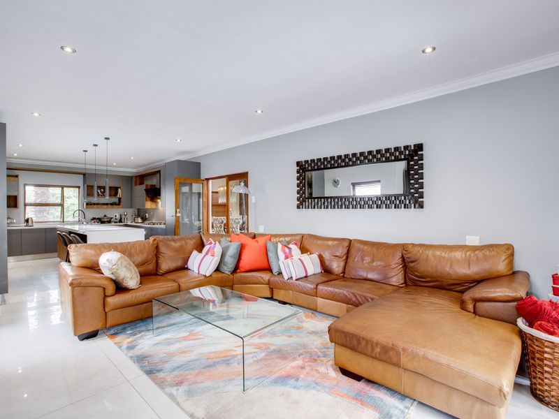 Spacious open-plan living area featuring modern tiled floors, recessed lighting, and a seamless transition into a contemporary kitchen with a central island.