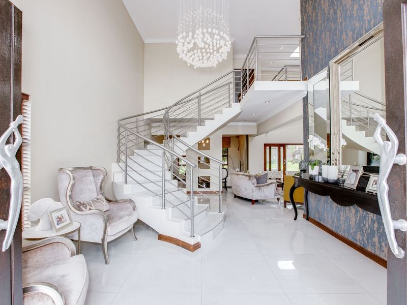 Grand entrance hall featuring a striking spiral staircase with stainless steel balustrades, polished tiled flooring, and elegant feature wall detailing.