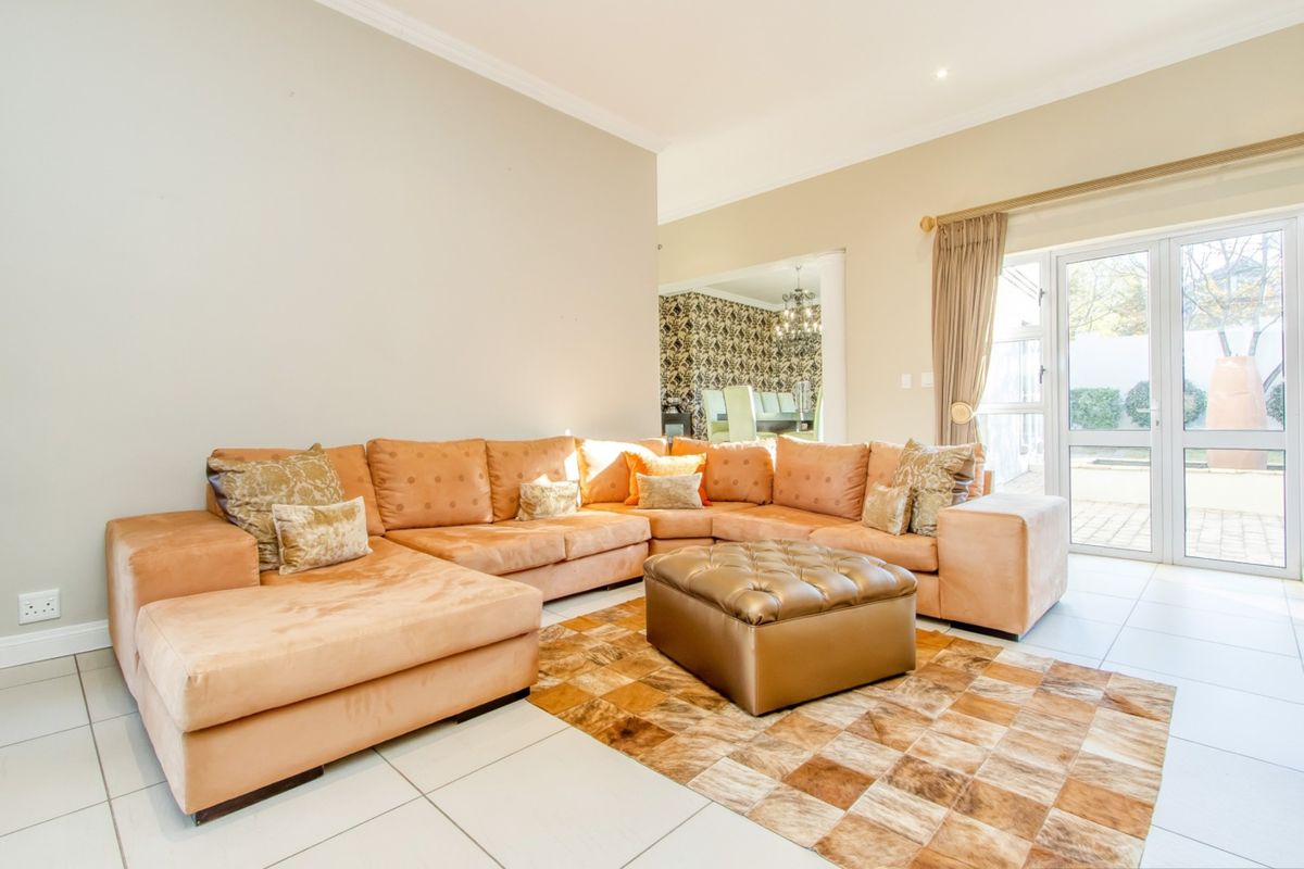 Spacious living room featuring neutral tiled flooring, recessed lighting, and direct access to the outdoor area through a glass sliding door.