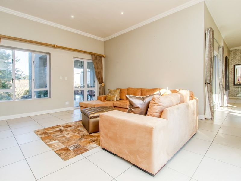 Spacious living room featuring neutral tiled flooring, recessed lighting, crown molding, and large windows providing natural light and access to the patio.
