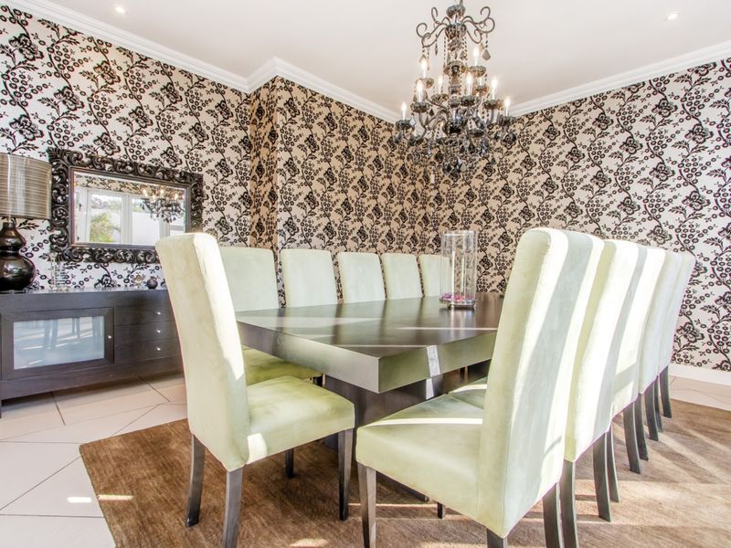 A formal dining room featuring decorative patterned wallpaper, crown molding, recessed lighting, and tiled flooring.