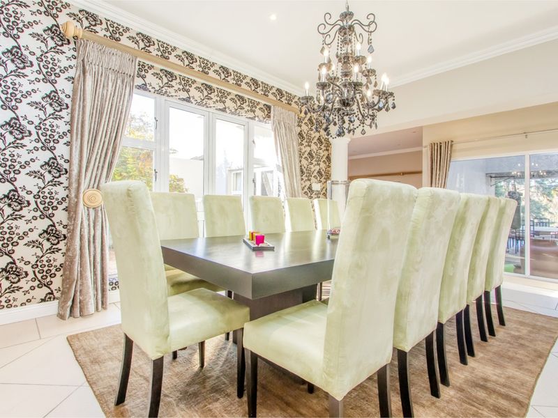 Spacious dining room featuring elegant chandelier lighting, tiled flooring, and large french doors providing natural light and access to the outdoor area.