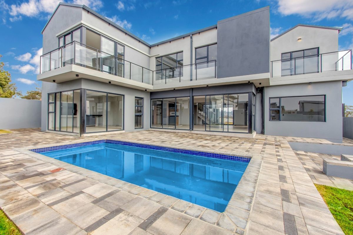 Modern double-storey residence featuring a paved patio area, swimming pool, and extensive glass sliding doors for seamless indoor-outdoor flow.
