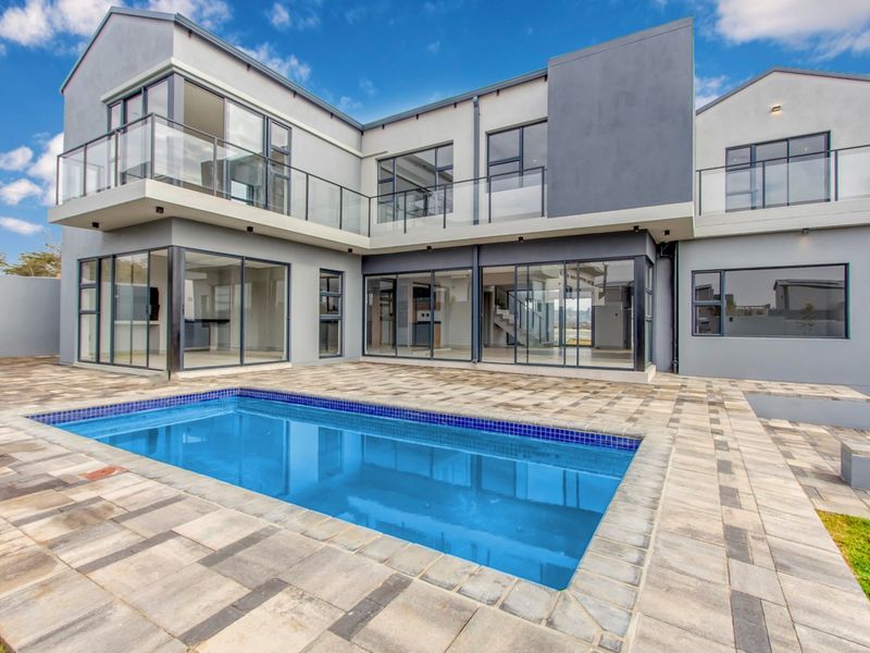 Modern double-storey residence featuring a paved patio area, swimming pool, and extensive glass sliding doors for seamless indoor-outdoor flow.