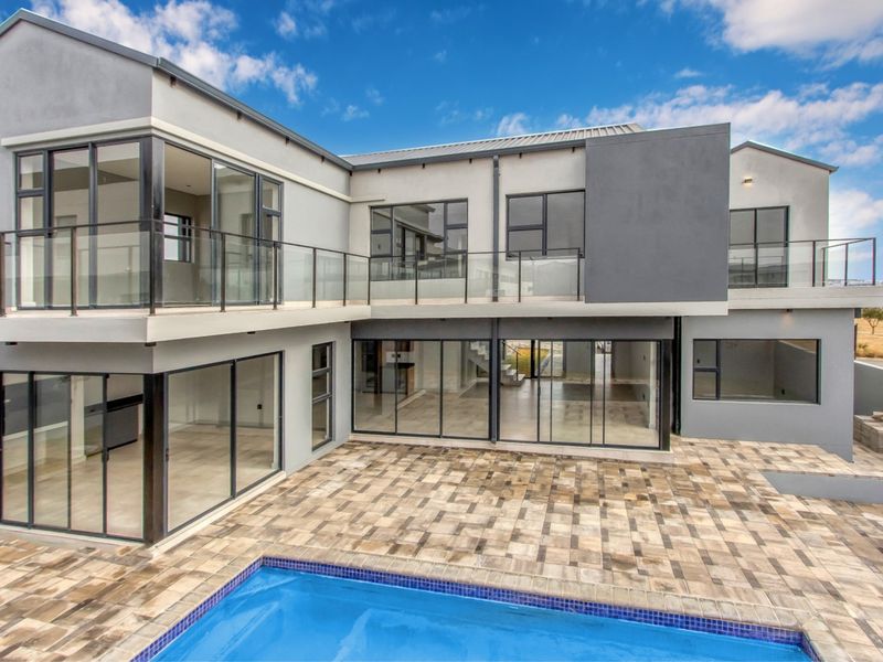 Modern double-story rear elevation featuring a paved patio, swimming pool, and extensive glass sliding doors leading to open-plan living areas.