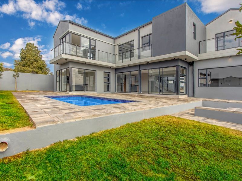 Modern double-story residence featuring a rear patio, swimming pool, and extensive glass sliding doors opening to a landscaped garden.