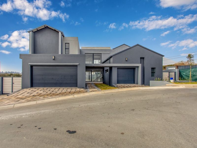 Modern double-story residential home featuring a sleek dark grey facade, double garage, and paved driveway entrance.