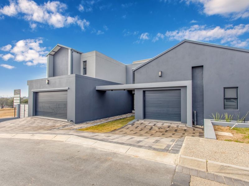 Modern double-story residential property featuring a contemporary grey facade, double garage, and paved driveway entrance.