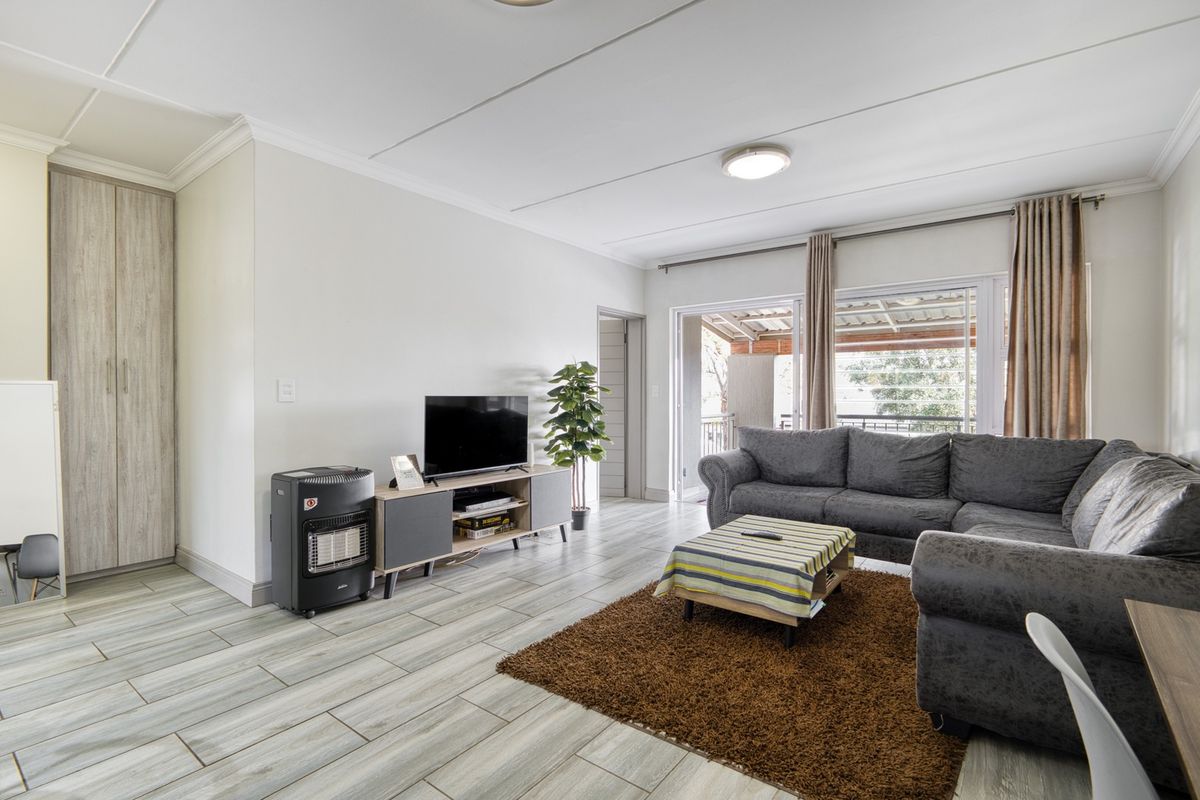 Spacious living room featuring modern tiled flooring, built-in storage cabinetry, and large sliding glass doors providing access to the outdoor area.
