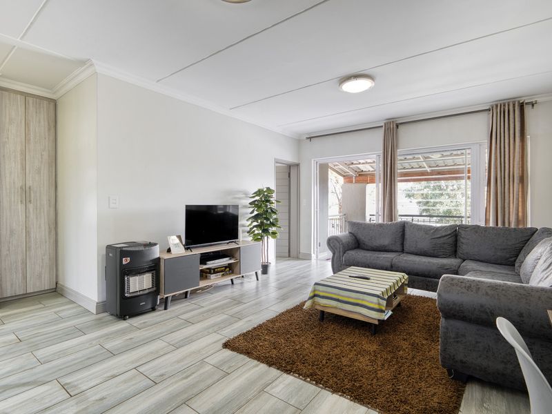 Spacious living room featuring modern tiled flooring, built-in storage cabinetry, and large sliding glass doors providing access to the outdoor area.