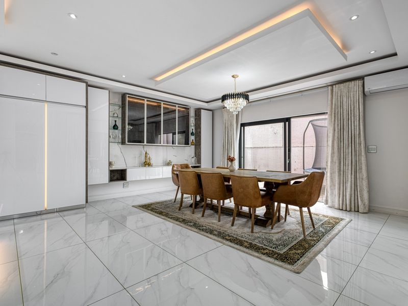 Modern dining room featuring high-gloss built-in cabinetry, marble-look tiled flooring, a sophisticated coffered ceiling with recessed lighting, and large sliding doors leading to the exterior.