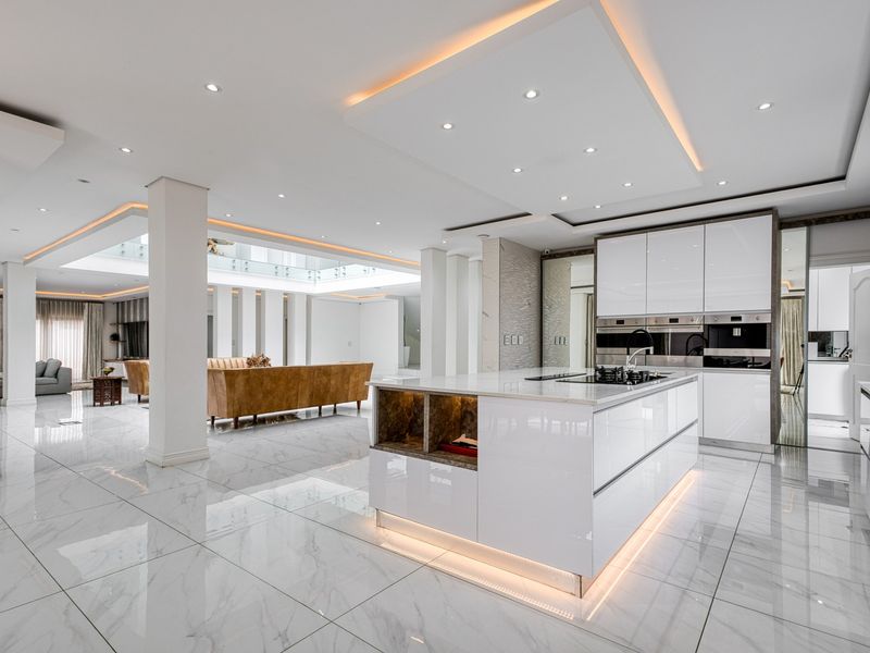 Spacious open-plan living area featuring a modern kitchen with a central island, high-gloss cabinetry, integrated appliances, and elegant marble flooring throughout.