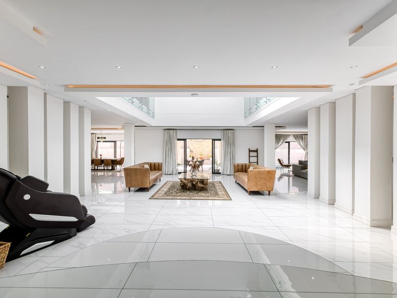 Spacious open-plan living area featuring high-end marble flooring, recessed ceiling lighting, and a central atrium skylight providing abundant natural light.