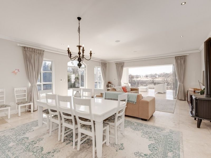 Spacious open-plan living and dining area featuring tiled floors, a freestanding fireplace, and large stacking doors opening to an outdoor patio.