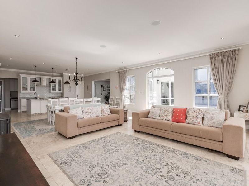 Spacious open-plan living and kitchen area featuring stone tile flooring, recessed lighting, a modern kitchen island, and a cozy wood-burning fireplace.