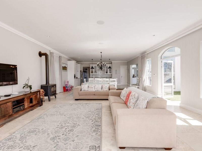 Spacious open-plan living and dining area featuring tiled floors, recessed lighting, and a cozy freestanding fireplace, with direct access to the outdoor space.