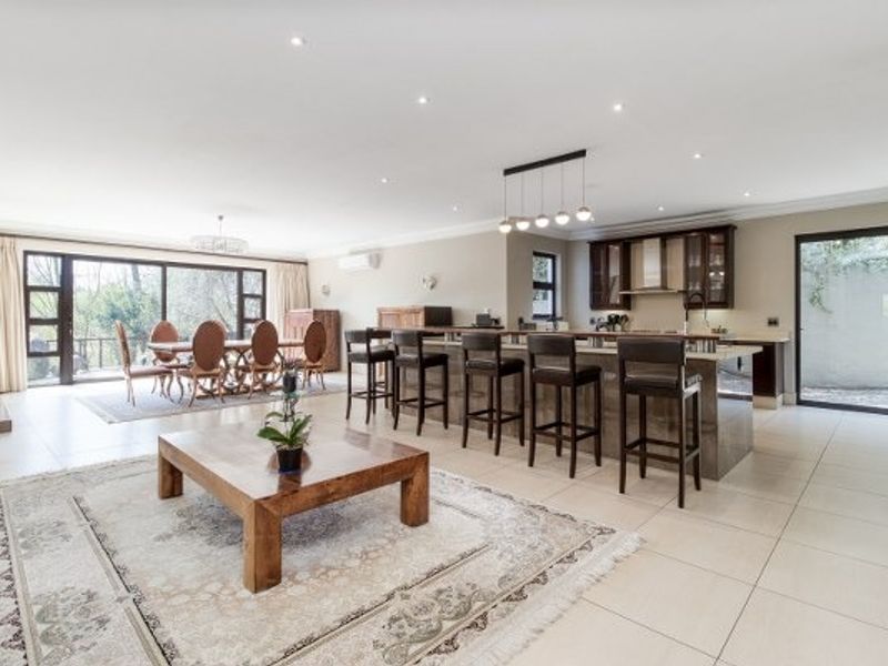 Spacious open-plan living and dining area featuring a modern kitchen with a large island, tiled floors, and expansive sliding doors leading to the outdoors.