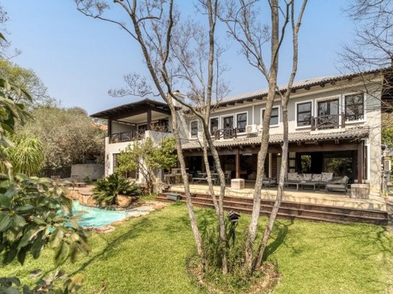 Rear view of a two-story house featuring a swimming pool, expansive covered patio, timber decking, and a well-maintained garden.