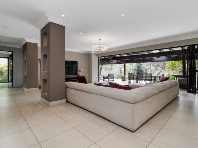 Spacious open-plan living area featuring tiled floors, recessed lighting, and seamless indoor-outdoor flow through large bi-fold doors to a covered patio.