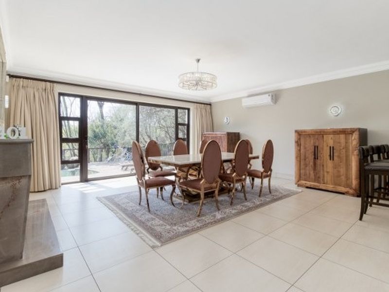 Spacious dining room featuring large sliding glass doors, tiled flooring, a stone fireplace surround, and a split-system air conditioner.