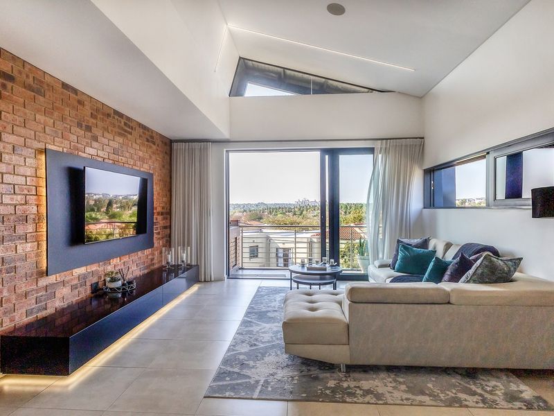 Modern living room featuring an exposed brick wall, high raked ceilings with clerestory windows, large format floor tiles, and direct access to a balcony.