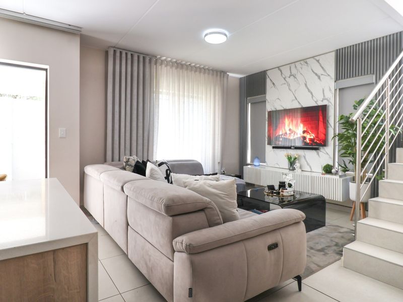 Modern living room featuring a marble-look feature wall, tiled flooring, and a staircase with a sleek metal railing.
