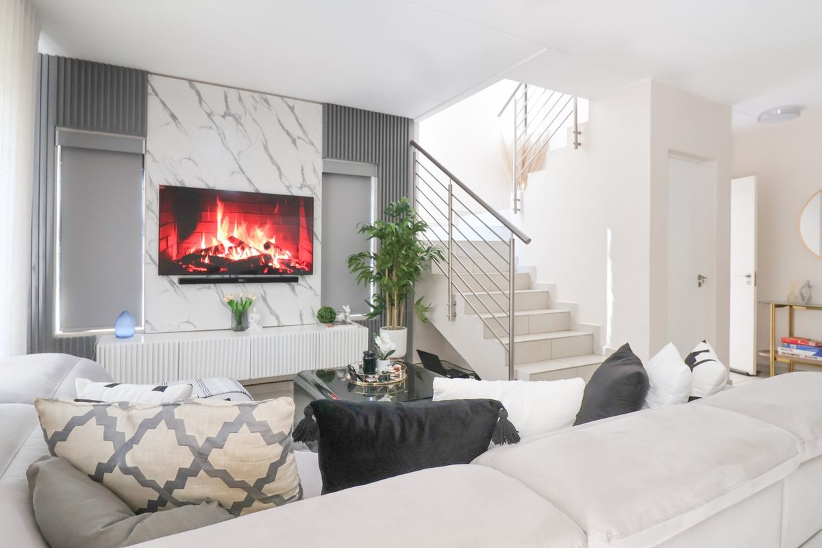 Modern living room featuring a marble-look feature wall, sleek staircase with stainless steel balustrade, and bright, contemporary finishes.