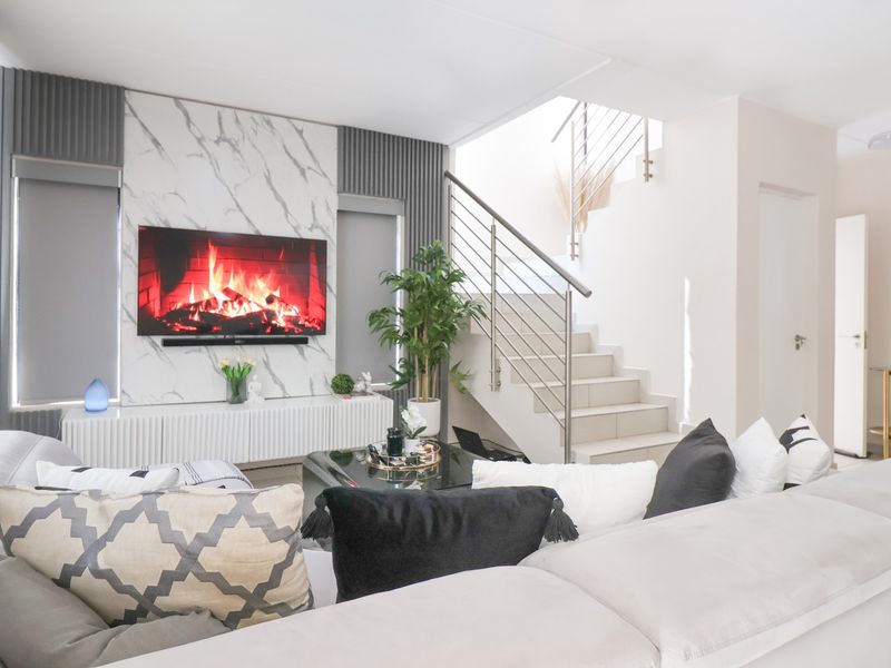 Modern living room featuring a marble-look feature wall, sleek staircase with stainless steel balustrade, and bright, contemporary finishes.