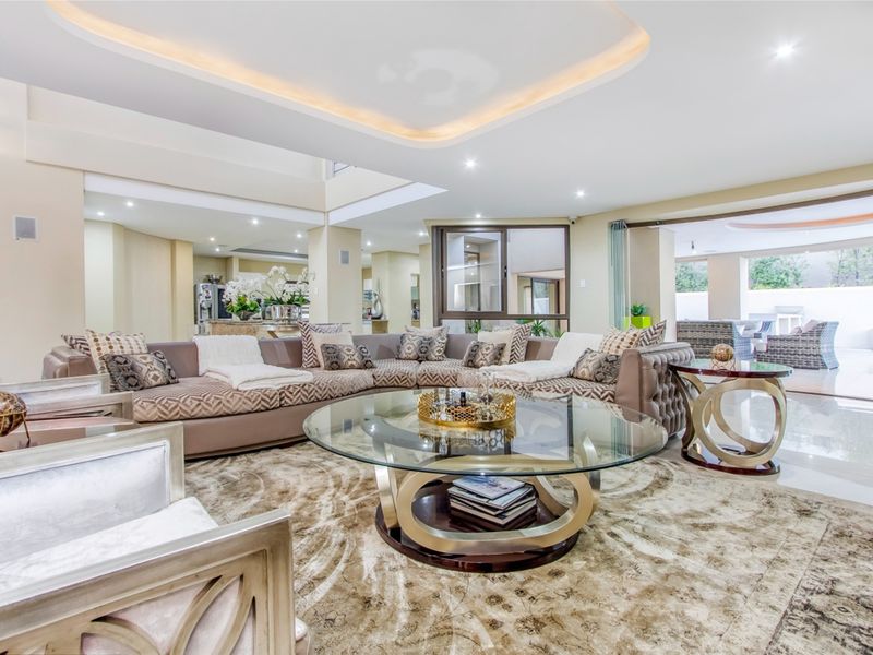Spacious open-plan living area featuring high-end finishes, recessed cove lighting, and seamless flow to the outdoor patio through large sliding glass doors.