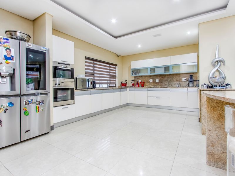 Modern kitchen featuring white cabinetry, stone countertops, built-in oven and microwave, recessed lighting, and polished tile flooring.