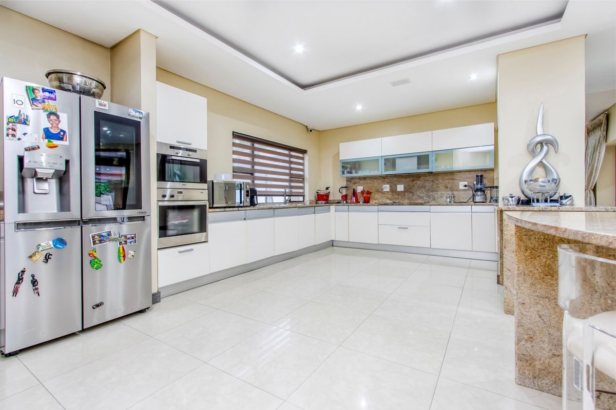 Modern kitchen featuring white cabinetry, stone countertops, built-in oven and microwave, recessed lighting, and polished tile flooring.