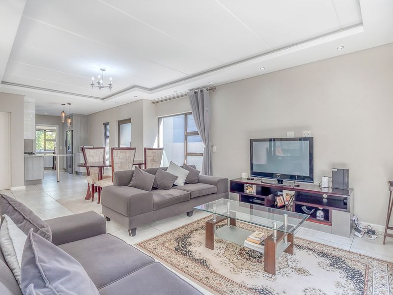 Spacious open-plan living and dining area featuring tiled floors, recessed ceiling lighting, and a seamless flow into the modern kitchen space.