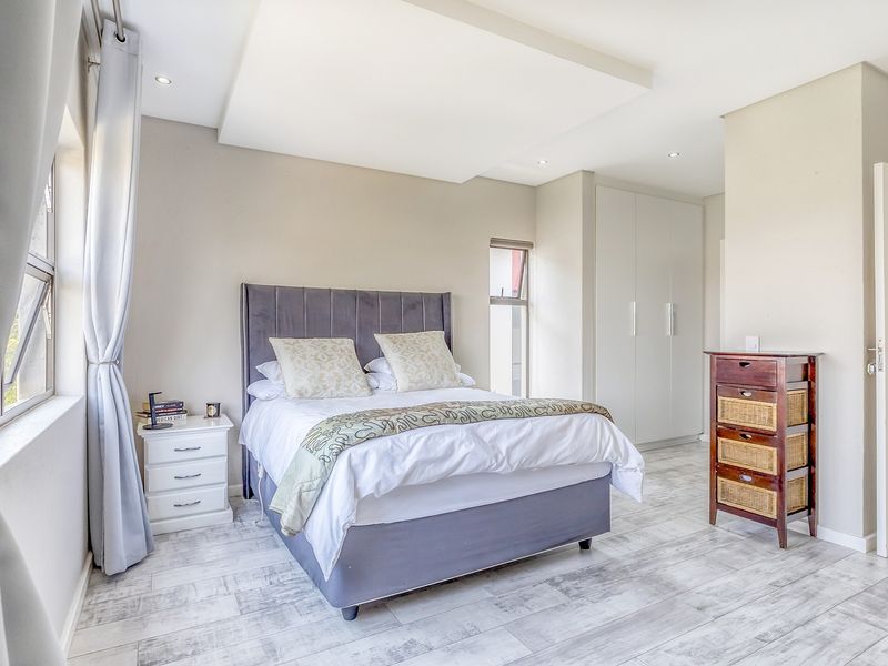 A well-maintained bedroom featuring built-in cupboards, recessed ceiling detail with downlights, and modern tiled flooring.