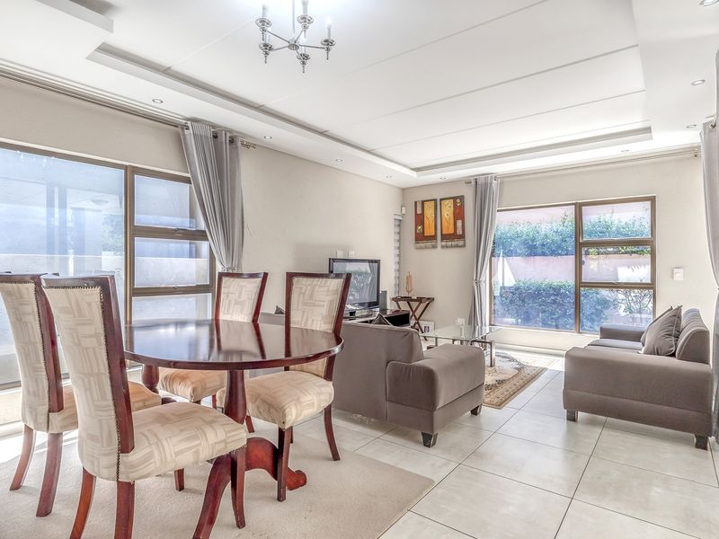 Spacious open-plan living and dining area featuring tiled floors, recessed ceiling lighting, and large aluminium-framed windows providing ample natural light.