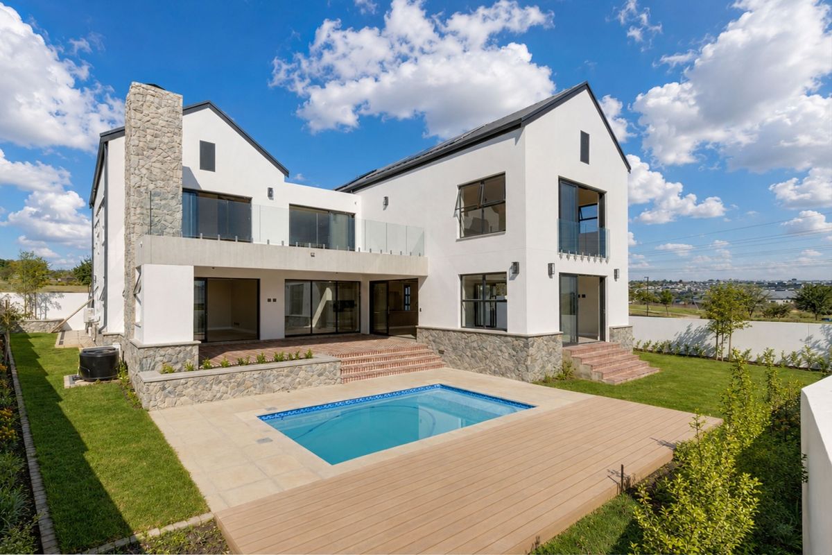 Modern double-story residence featuring a rear patio, swimming pool, timber decking, and stone-clad architectural details set within a landscaped garden.