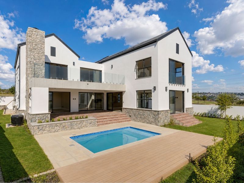 Modern double-story residence featuring a rear patio, swimming pool, timber decking, and stone-clad architectural details set within a landscaped garden.