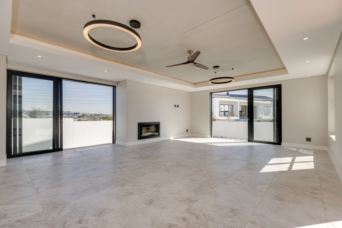Spacious, modern living area featuring large sliding glass doors, a built-in fireplace, recessed ceiling details, and contemporary tiled flooring.