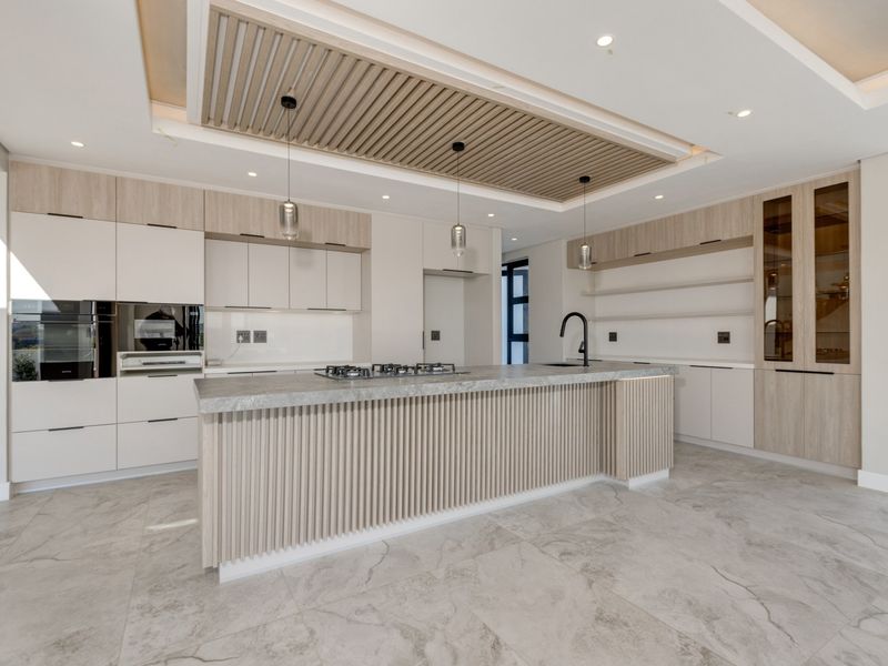Modern, high-end kitchen featuring a large island with stone countertops, integrated appliances, custom slatted ceiling detail, and premium cabinetry finishes.