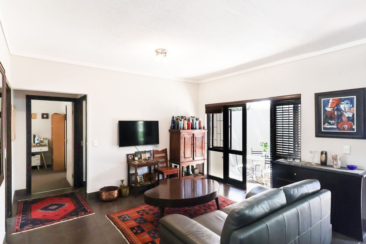 A well-lit living room featuring tiled flooring, coved ceilings, and a sliding glass door providing direct access to an outdoor patio area.
