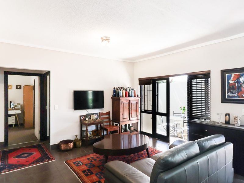 A well-lit living room featuring tiled flooring, coved ceilings, and a sliding glass door providing direct access to an outdoor patio area.